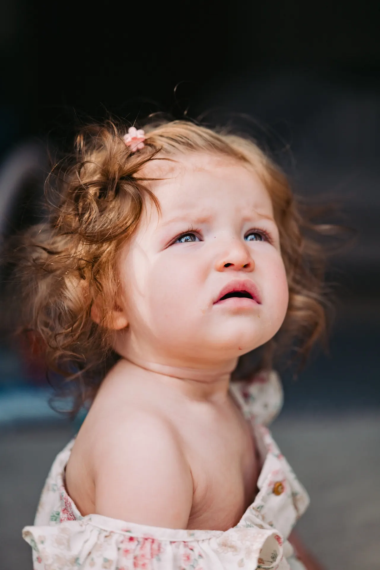 Toddler girl with curly hair looking up