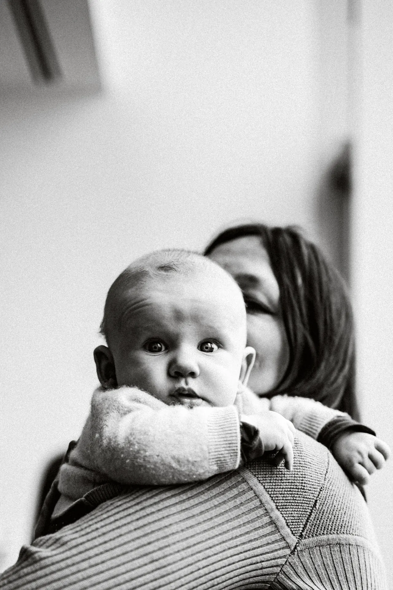 Baby resting on parent's shoulder, black and white