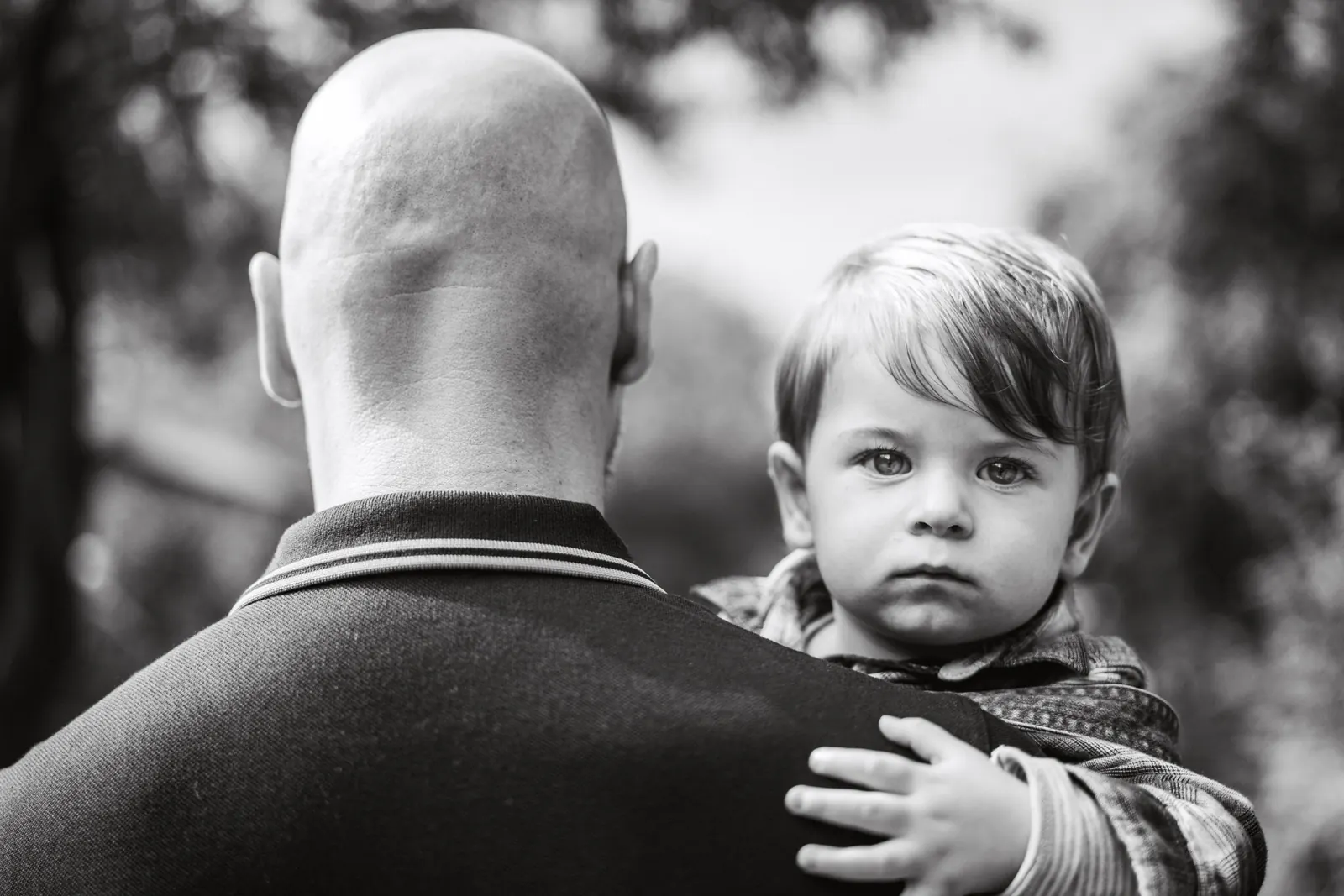 Father holding toddler over shoulder, black and white