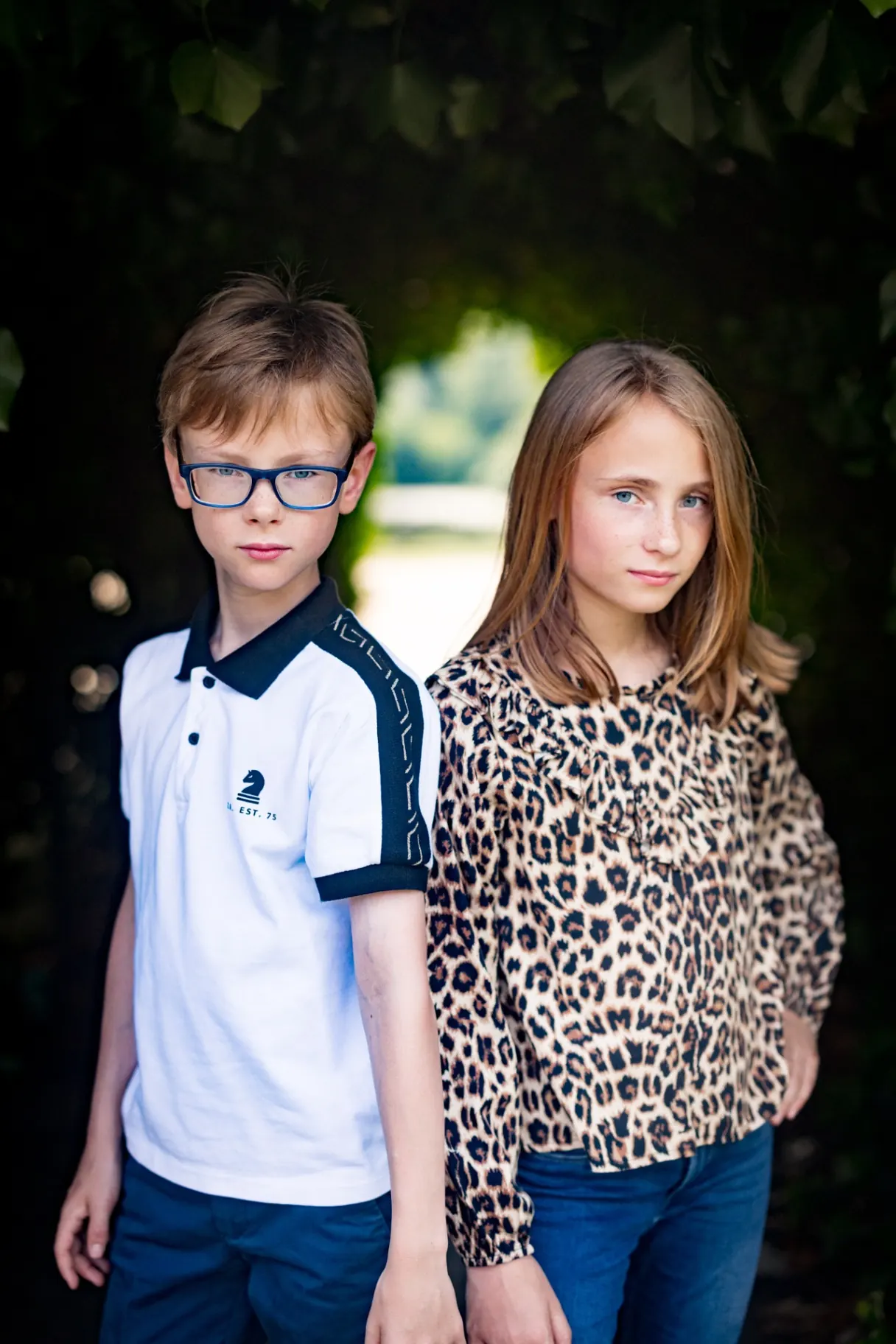Brother and sister portrait under leafy archway