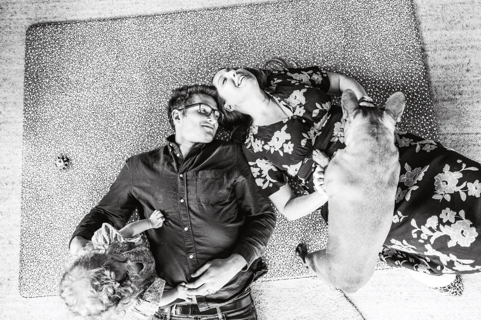 Family lying on rug with dog, overhead black and white