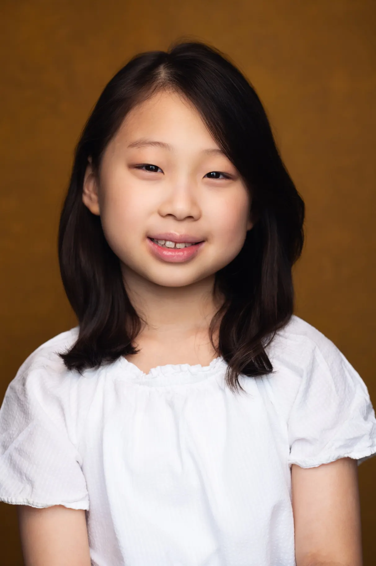 Young girl smiling studio portrait on ochre backdrop