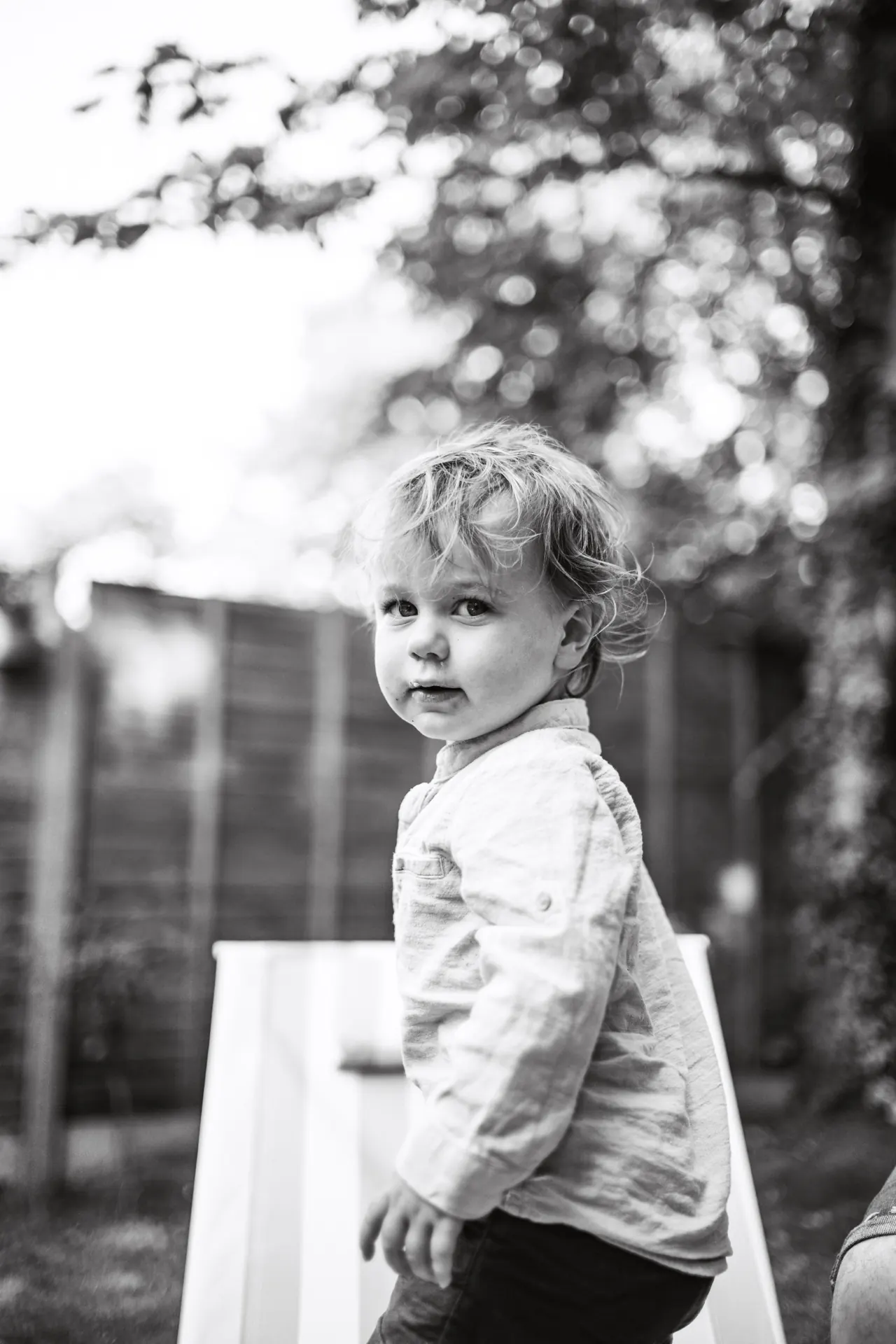 Toddler looking over shoulder in garden, black and white