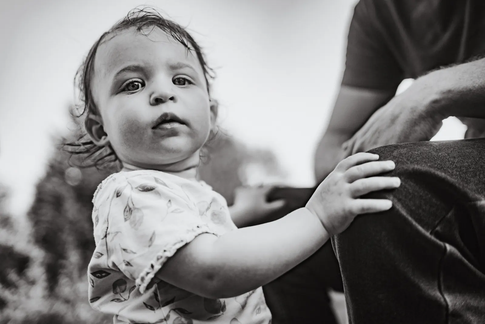 Baby girl reaching for parent, black and white close-up