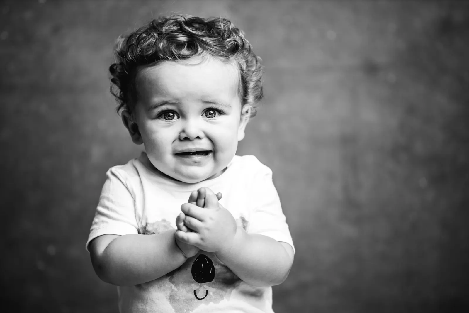Toddler clapping hands, black and white studio portrait