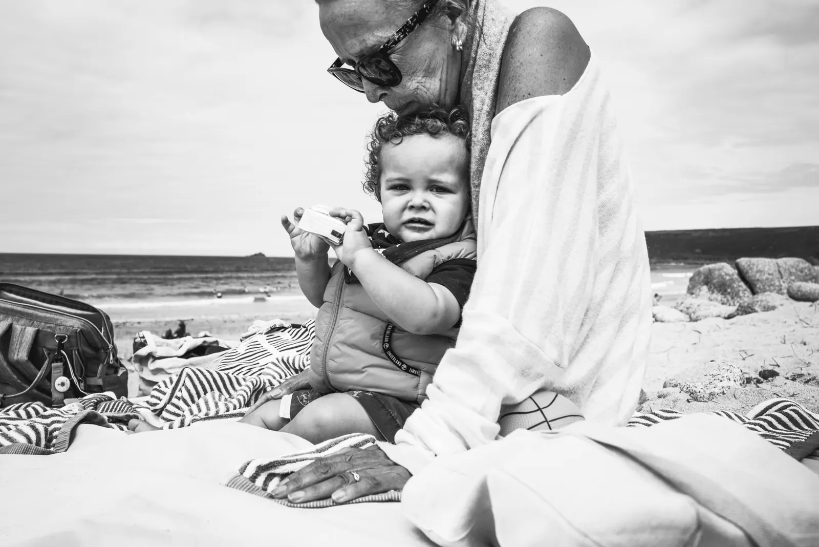 Grandparent holding toddler on the beach, black and white