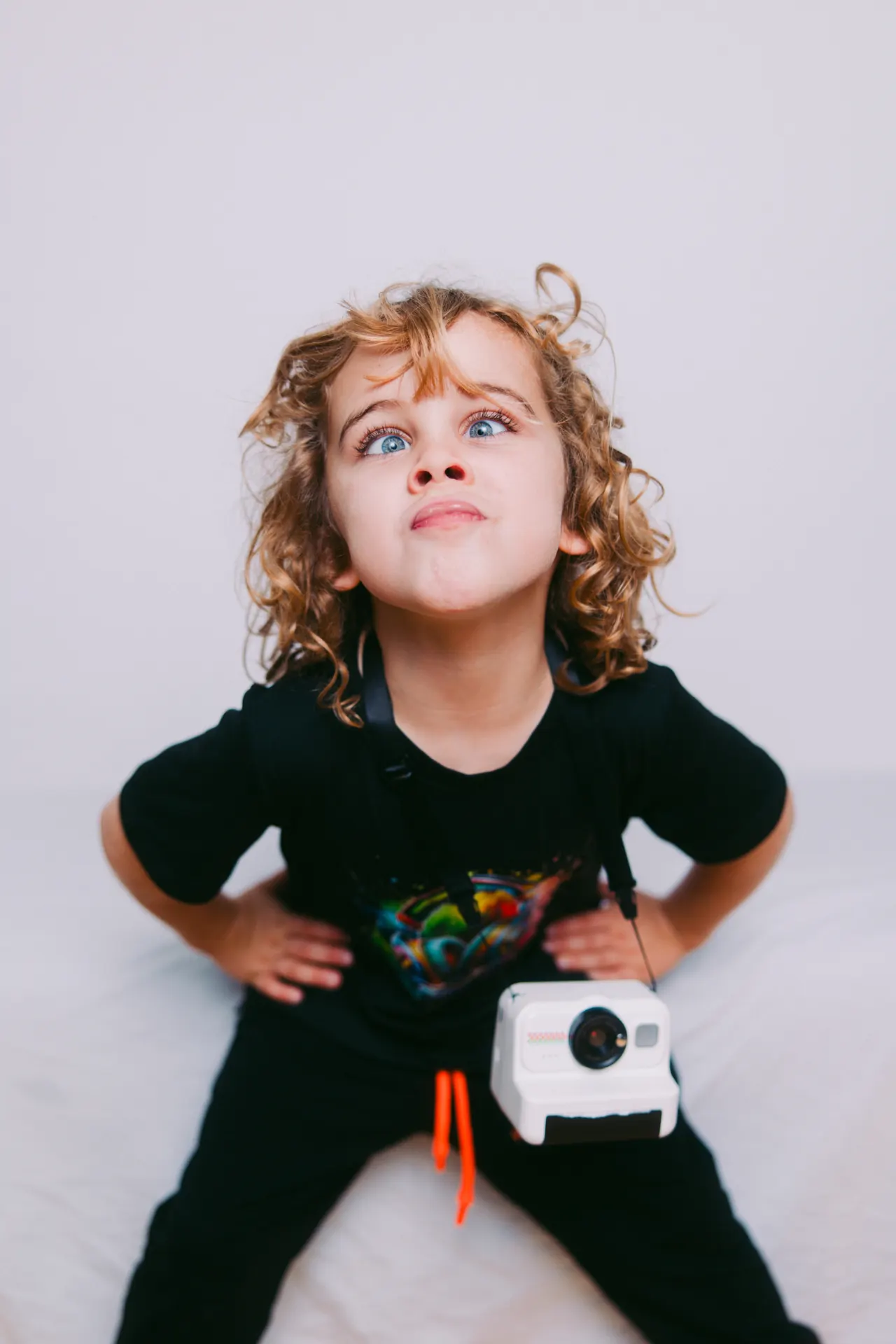 Curly-haired child making a funny face with toy camera
