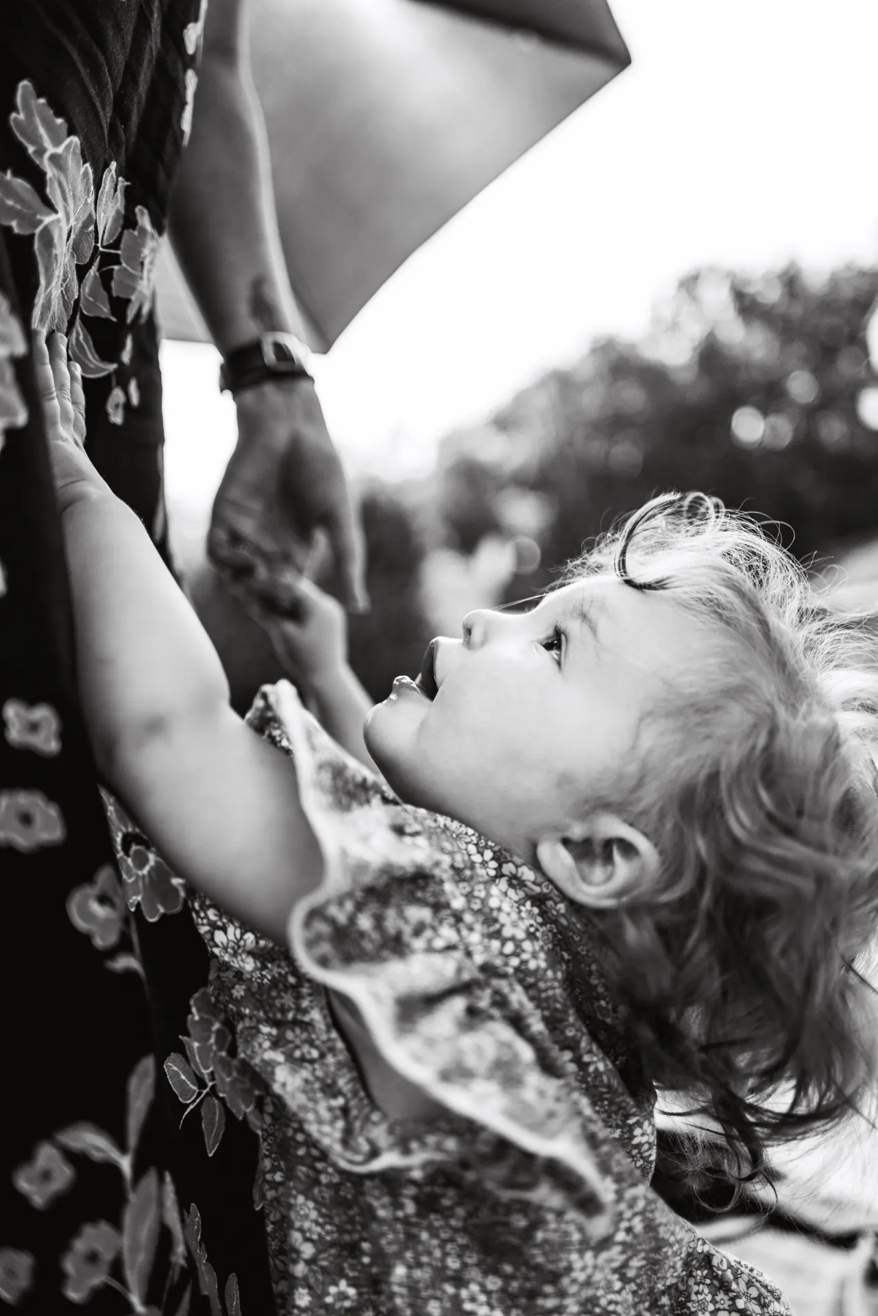 Toddler reaching up toward an adult, black and white