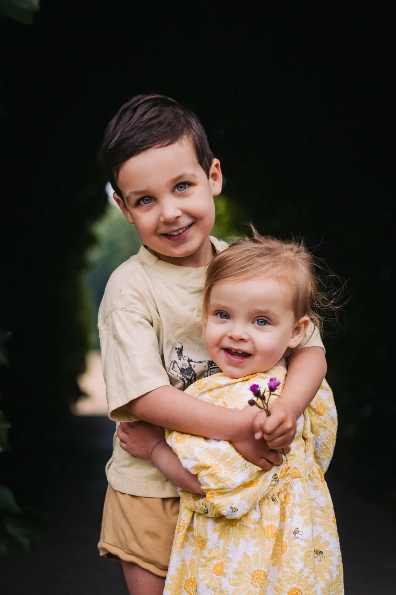 Big brother hugging little sister in a garden
