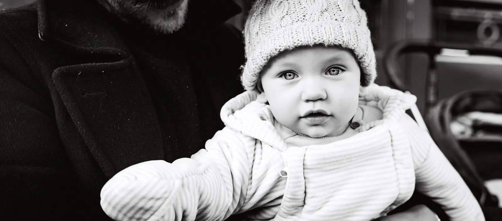Father holding baby in knitted hat, black and white