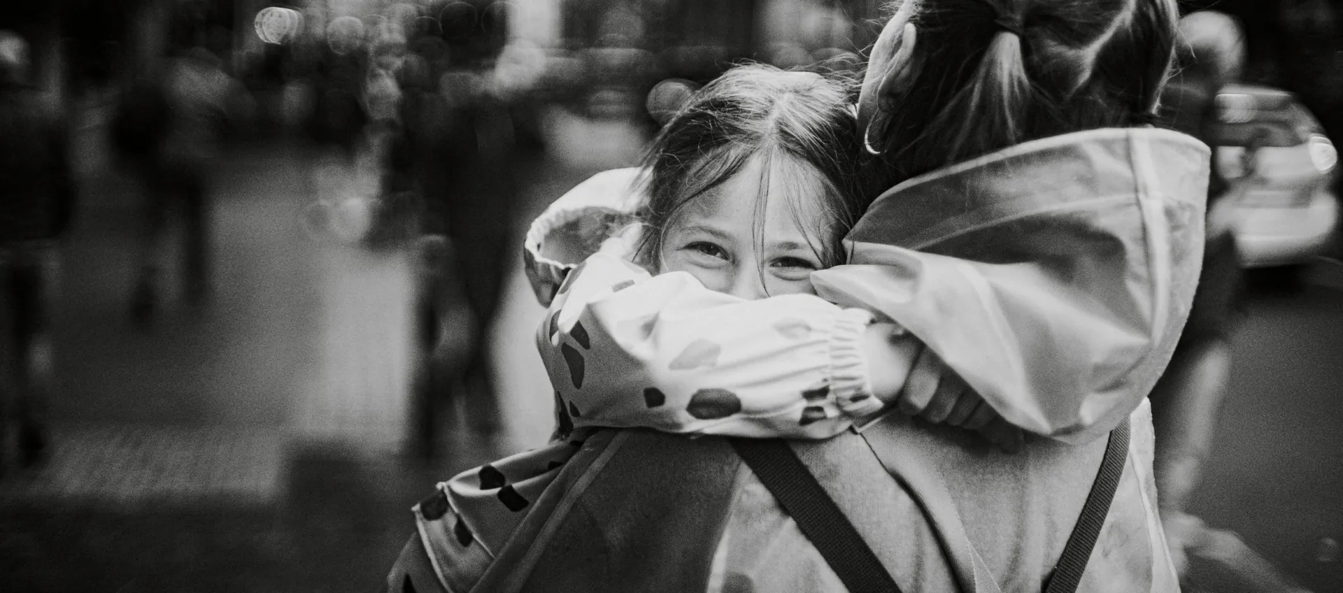 Black and white photo of a child hugging a parent outdoors