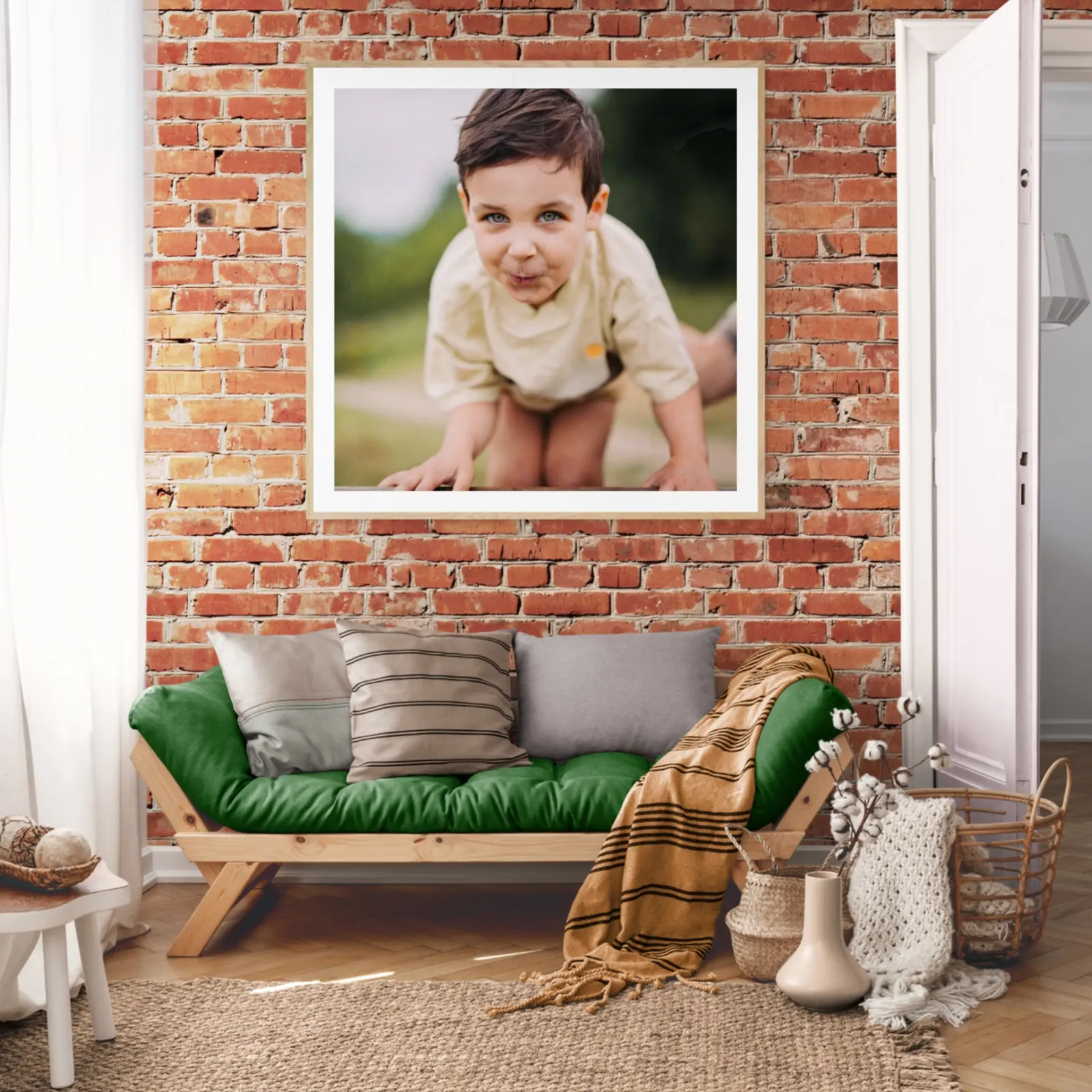 Framed outdoor portrait of a child hanging above a green sofa on a brick wall